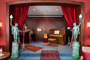 曼海姆Tante ALMA's Mannheimer Hotel的一间房间,里面装有钢琴和两座雕像
