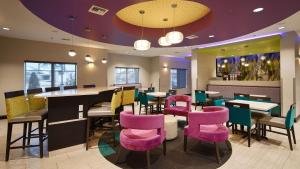 查尔斯湖Best Western Plus Prien Lake Hotel & Suites - Lake Charles的餐厅设有粉红色和紫色的椅子和桌子