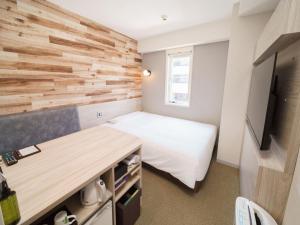 东京横丁品川青物超级酒店的一间小卧室,配有一张床和木墙
