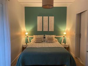 朗通Maison Blanche的一间卧室配有一张带两盏灯和一堵绿色墙壁的床。