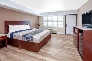 海港城Travelodge by Wyndham Harbor City的配有一张床和一台平面电视的酒店客房