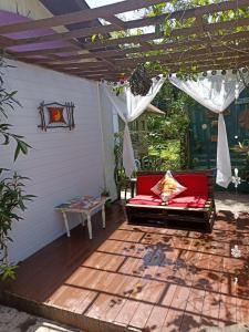 蜜岛RECANTO DO SOL "Aluguel de quartos - Hospedagem Simples"的凉棚下带红色沙发的庭院
