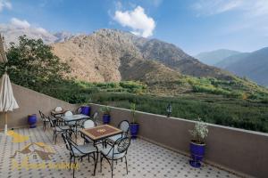 伊姆利尔Mount Toubkal Lodge的庭院配有桌椅,背景为山脉