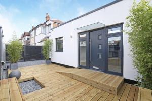 Streatham ValeStreatham House - Modern Detached 2 Bedroom House in Streatham Common的一个带木甲板和房子的花园