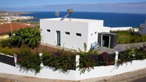 Las CrucesLas Pardelas, Ferienhaus mit Meer-, Küsten- und Bergblick im grünen Norden Teneriffas的白色房子的一侧有鲜花