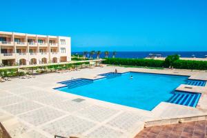 赫尔格达万岁蓝度假村和沙姆沙伊赫纳加潜水酒店（仅限成年人）的一座大型游泳池,毗邻一座建筑和大海