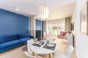 尤斯托尼莫斯基Ustronie Apartments 20 m do plaży的客厅配有蓝色的沙发、桌子和椅子