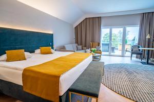 鲁恰内尼达Mazurski Raj - Hotel, Marina & Spa的酒店客房设有一张大床和一间客厅。