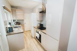 诺里奇Newly Refurbished House - 10 Minute Walk From City Centre的厨房配有白色橱柜和炉灶烤箱。