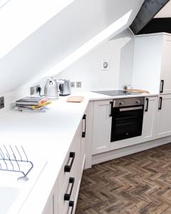 阿什顿下安林恩Urban Loft Apartment • 1 Bedroom • Manchester的厨房配有白色橱柜和黑烤箱。