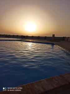 Dawwār ‘Abd al Qādir Qāsimشاليه مرقيا بالساحل الشمالي صف اول بحر的一座享有日落美景的游泳池
