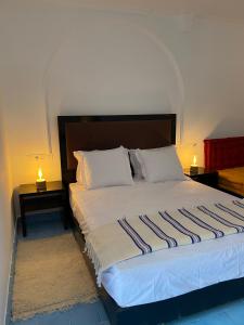 艾西拉Dmina House的一间卧室配有一张带两张桌子和两盏灯的床。