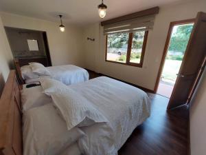 塔巴贝拉Quinta San Felipe的一间卧室设有两张带白色床单的床和窗户。