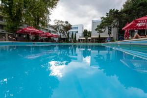 尼普顿Cocor Spa Hotel的一个带蓝色水和红色遮阳伞的游泳池