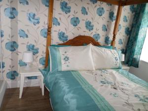 洛斯托夫特日出度假屋的一间卧室配有一张蓝色花卉壁纸床