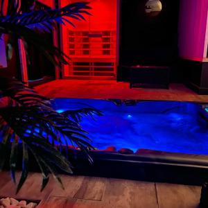 格勒诺布尔La suite Grenoble spa jacuzzi et sauna privatif的配有红色和蓝色灯光的客房内的热水浴池