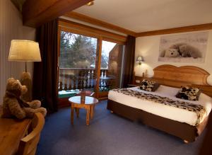 莱德萨阿尔卑斯Hôtel Serre Palas的酒店客房带一张床和泰迪熊