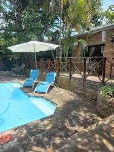 圣卢西亚African Dreamz Guest House的一个带两把椅子和一把遮阳伞的游泳池