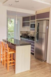 巴拉奈里奥-坎布里乌Morada do Estaleiro的厨房配有不锈钢冰箱和木椅
