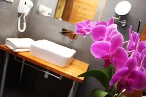 大波兰地区格罗济斯克Zajazd w Białej的浴室设有水槽,在柜台上种植紫色鲜花