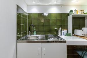 赫维兹Origo Vendégház的厨房设有水槽和绿色瓷砖墙。