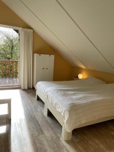 GasselteTofino, een comfortabel vakantiehuis naast een bos en zwemmeer的一张位于带大窗户的房间内的床铺