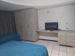 纳塔尔Atlântico Flat Natal的一间卧室配有一张床和一张书桌及电视