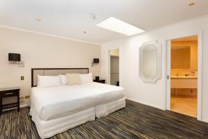 基督城菲诺酒店及套房 的一间带白色大床的卧室和一间浴室