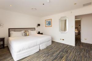 基督城菲诺酒店及套房 的白色卧室设有一张大床和镜子