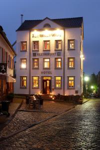 尼德根Zur Ewigen Lampe Romantisches Landhotel & Restaurant的夜间在鹅卵石街道上点亮酒店