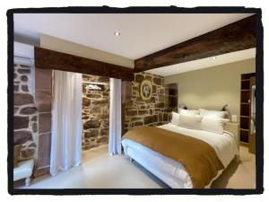 圣让皮耶德波尔易博尔纳特住宿加早餐旅馆的一间卧室设有一张带石墙的大床