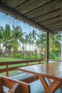 大塞拉Welove Beach House-Pés na areia Quintal dos Sonhos的棕榈树甲板上的木桌和椅子