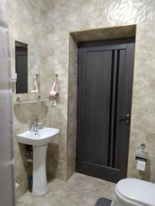 塔什干Chinara Guest House Airport的一间带水槽和卫生间的浴室以及一扇黑色的门。