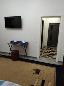 塔什干Chinara Guest House Airport的一间设有桌子的房间和墙上的电视