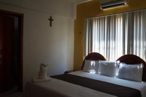 帕拉伊索DON CELES的一间卧室设有两张床,窗户上有一个十字架
