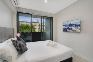 悉尼Coogee Studio Apartments的卧室设有白色的床和大窗户