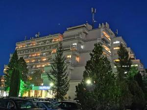 科瓦斯纳Hotel Montana - Covasna的一座大型建筑,前面有汽车停放