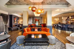 伯恩茅斯Queens Hotel & Spa Bournemouth的一间带橙色沙发的客厅和一间酒吧