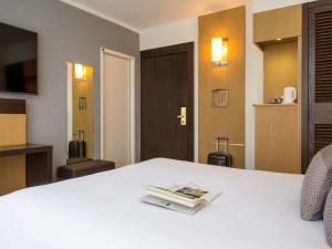 日内瓦诺富特日内瓦中心酒店的酒店客房,配有一张床铺,上面有一本书