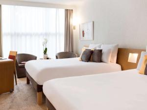 日内瓦诺富特日内瓦中心酒店的酒店客房,配有两张床和椅子