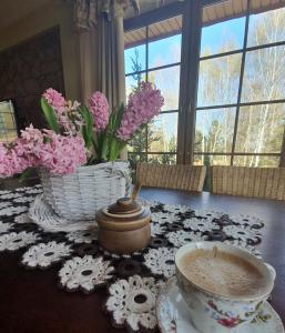 奥尔什丁Zacisze Jurajskie的一张桌子,上面放着一杯咖啡和一篮鲜花
