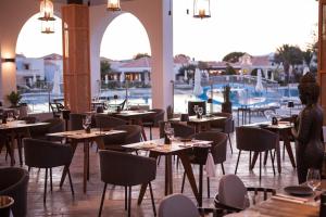 马斯蒂查里Neptune Luxury Resort的一间带桌椅的餐厅和一个游泳池