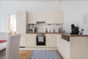 维也纳Apartment France | Operastreet的厨房配有白色橱柜和炉灶烤箱。