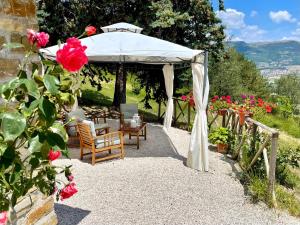 古比奥La Panoramica Gubbio - Maison de Charme - Casette e appartamenti self catering per vacanze meravigliose!的凉亭配有桌椅和鲜花