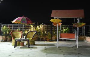 斋浦尔Laxmi Residence的庭院里配有两把遮阳伞和一张桌子及椅子