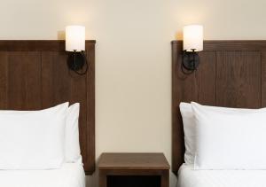 亨德森维尔Kanuga Inn & Lodging的酒店客房设有两张床和两盏墙上的灯。