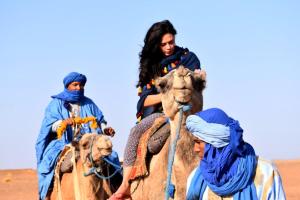 扎古拉Tikida Camp by tinfou的两个人骑在沙漠骆驼后面