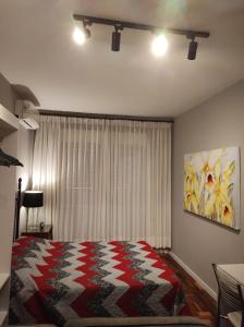 阿雷格里港Studioaconchegantepoa的一间卧室配有一张带红白毯子的床