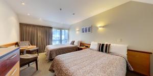 但尼丁Dunedin Leisure Lodge - Distinction的酒店客房配有两张床和一张书桌