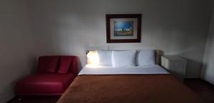 瓦哈卡市拉斯美洲旅馆的一间卧室配有一张床和一张红色椅子